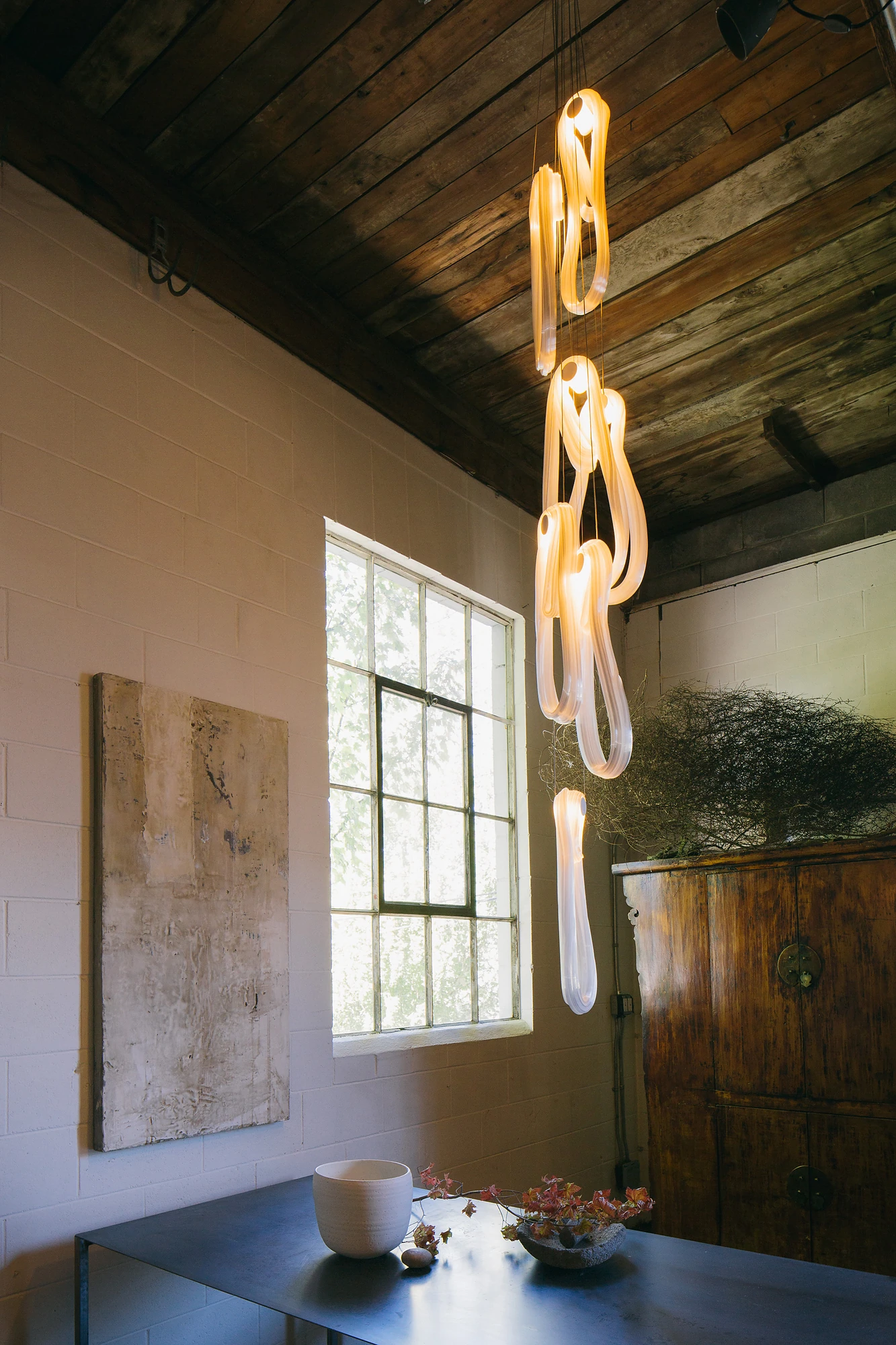 Sculptural translucent pendant column in a daylit atelier